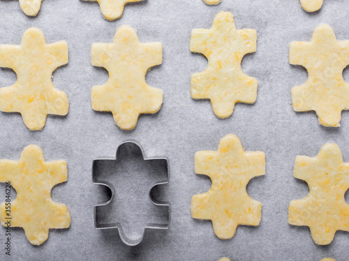 Raw puzzle shaped cookies and the puzzle mold on the oven tray 