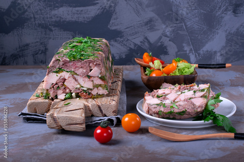Pork and beef terrine with herbs served with tomato salad. French cuisine aspic meal photo