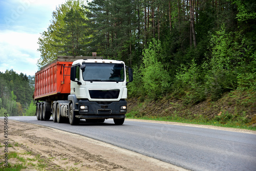 Truck with tipper semi trailer transported sand from the quarry on driving along highway. Modern Dump Semi-Trailer Rear Tipper Truck Trailer