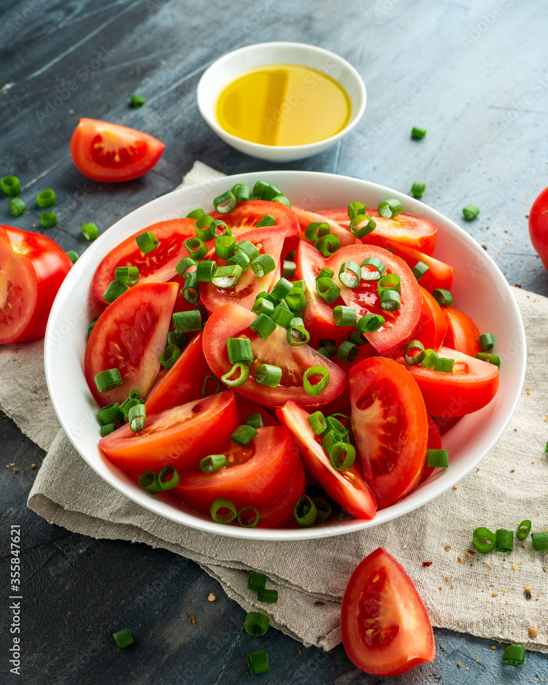 Tomato salad with spring onion and herbs in white bowl. Healthy summer food