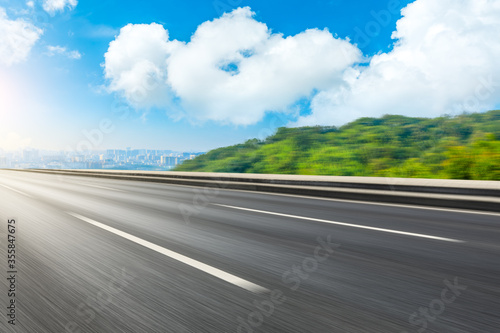 Motion blurred asphalt road and green mountain with city skyline in Hangzhou. © ABCDstock