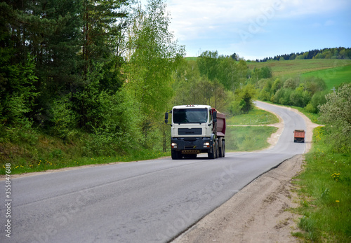 Tipper Dump Truck transported sand from the quarry on driving along highway. Modern Heavy Duty Dump Truck with unloads goods by itself through hydraulic or mechanical lifting © MaxSafaniuk