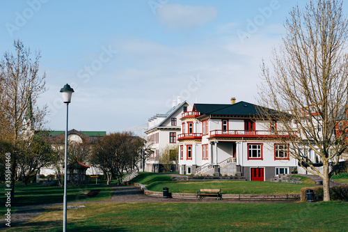 Beautiful white two-story house with a black roof, near the park in Reykjavik, the capital of Iceland. Spring town.