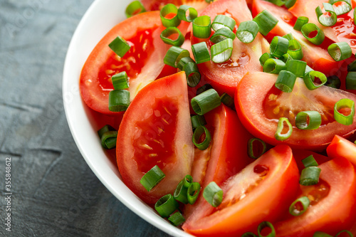 Tomato salad with spring onion and herbs in white bowl. Healthy summer food