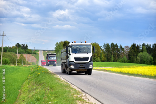 Tipper Dump Truck transported sand from the quarry on driving along highway. Modern Heavy Duty Dump Truck with unloads goods by itself through hydraulic or mechanical lifting