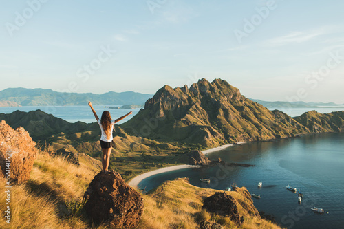 Woman with amazing view of Padar island in Komodo national park, Indonesia. Enjoying tropical vacation in Asia. Lifestyle travel concept. View from behind. photo
