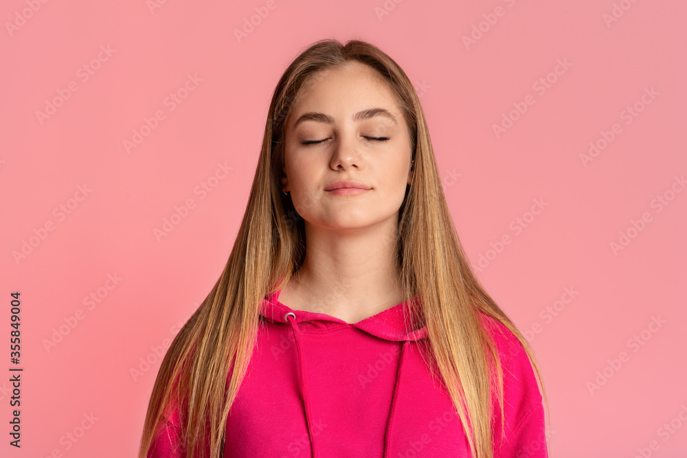 Fototapeta premium Teenager girl with closed eyes enjoy the moment, isolated on pink background