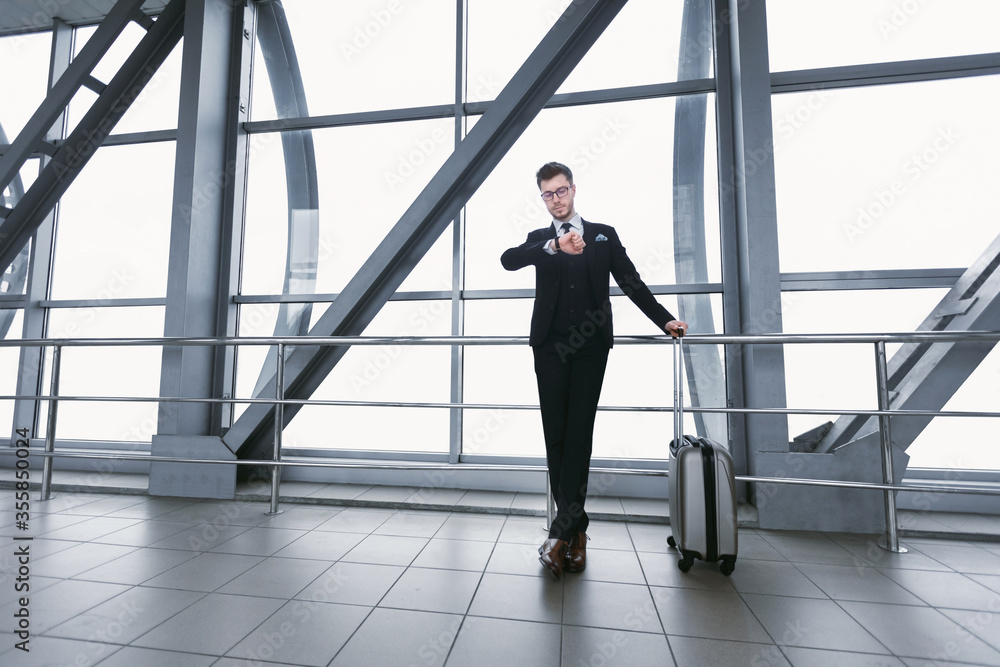 Urban business man standing in airport with suitcase