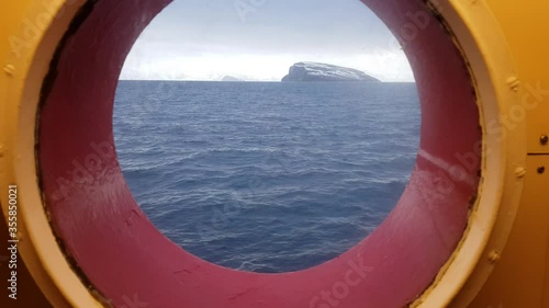 snowy mountain and waves on the arctic circle sea through a porthole