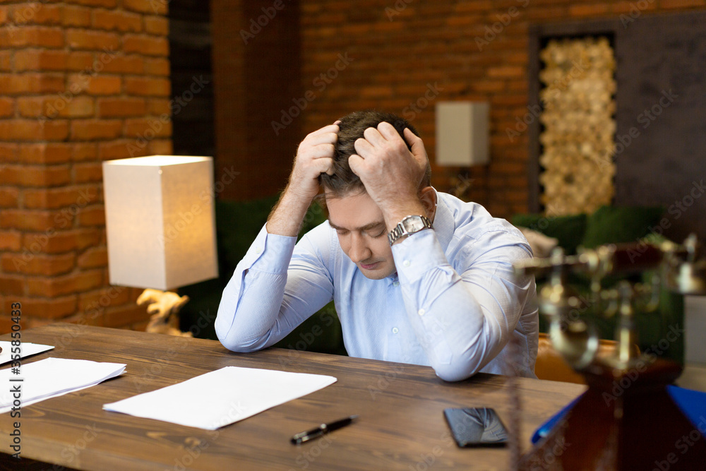 Obraz premium Critical error in documents. Portrait of a businessman at the table clutching his head.