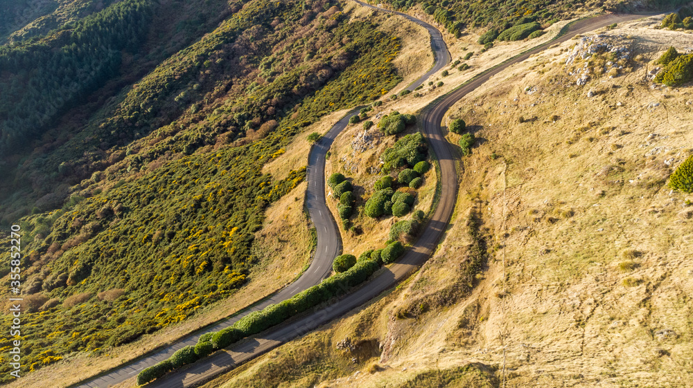 Aerial shot - Scenic view of Road at the peak at Bank Peninsula, Akaroa, New Zealand. Aerial shot - Scenic view of Road at the peak at Bank Peninsula, Akaroa, New Zealand.