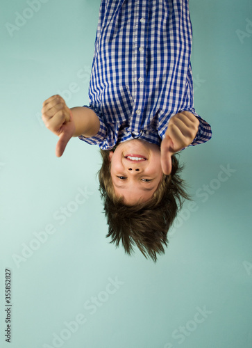 Happy boy hanging upside down, holding his hands in front of him