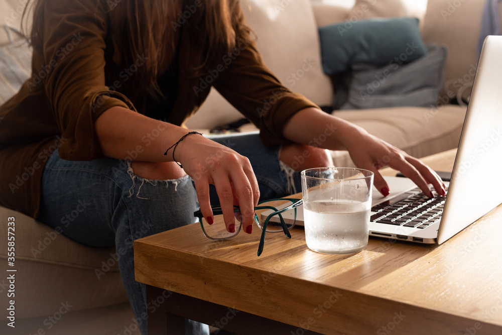 home work space - work from home concept - girl working or studying with a laptop sitting on a sofa by a wooden desk home work space - work from home concept - girl working or studying with a laptop sitting on a sofa by a wooden desk