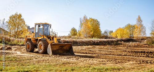large yellow wheel loader aligns a piece of land for a new building. Preparation of the land for the auction. Leveling the landscape and adding sand for construction.