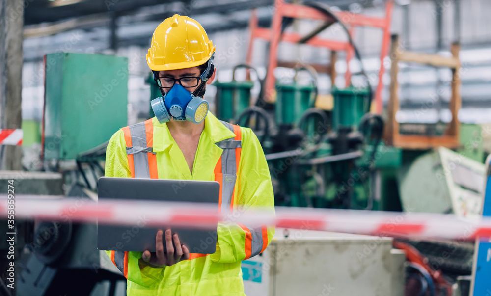 worker man caucasian wear a blue protective mask and safety jumpsuit uniform with yellow hardhat using laptop at factory worker man caucasian wear a blue protective mask and safety jumpsuit uniform with yellow hardhat using laptop at factory