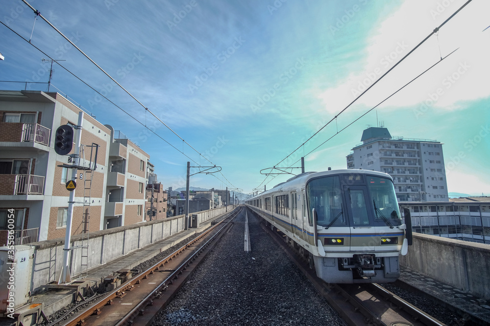 A train arriving at a station with houses and buildings along both sides of the tracks.