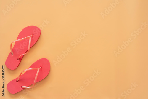 Red flip flops on sandy background with copy space.
