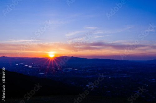 山に沈む夕焼けと河と平野