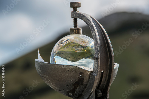 Meteorological heliograph situated in front of Zavizan mountain hut and meteorological station on the Velebit mountain in Croatia. Zavizan kosa is blurred and visible behind it. photo