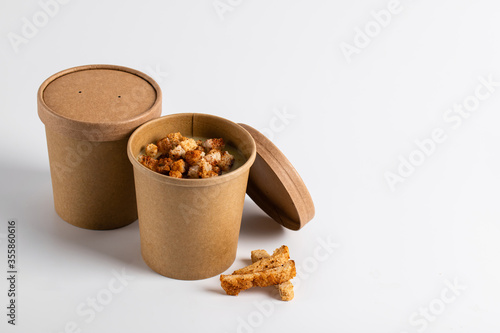 Potato cream soup with croutons in craft containers on a white background. Vegetable soup to go, takeaway food photo