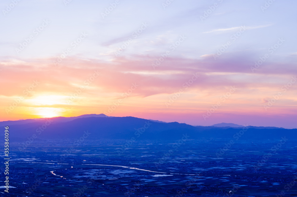 Fototapeta premium 山に沈む夕焼けと河と平野