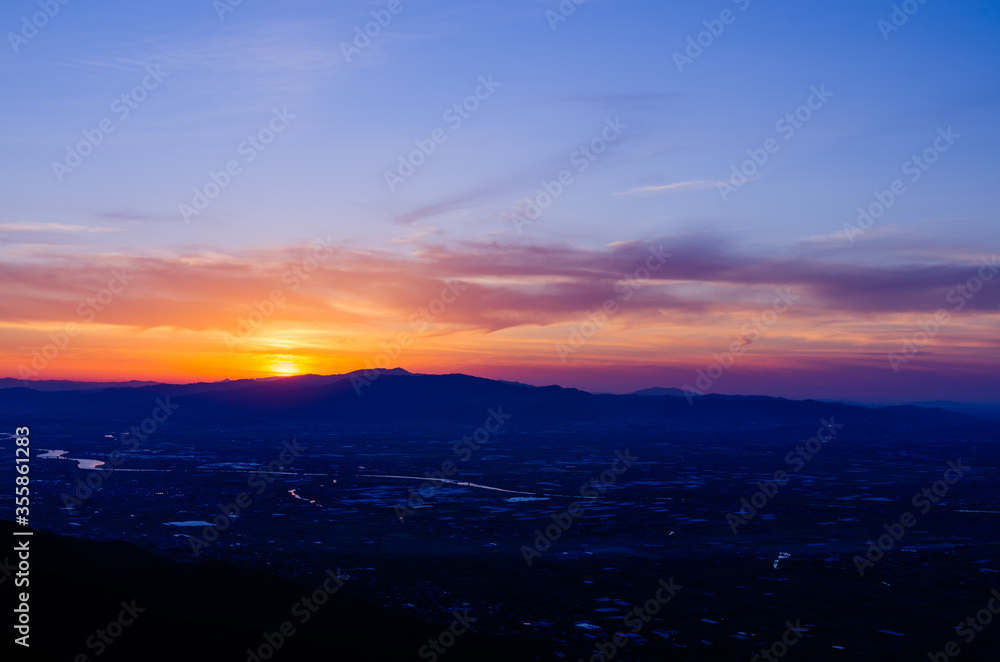 山に沈む夕焼けと河と平野