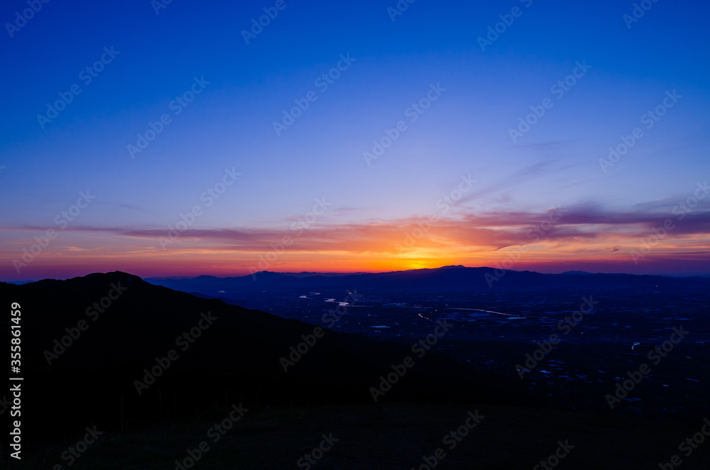 山に沈む夕焼けと河と平野