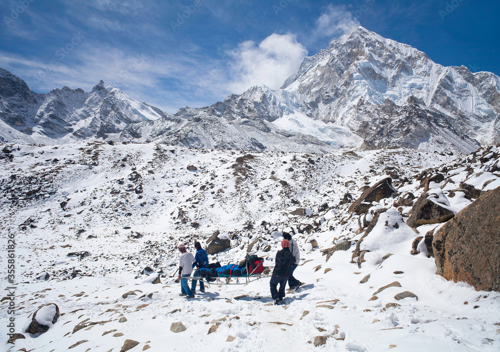 Unidentified Nepalese porters carrying an injured climber with altitude sickness for emergency evacuate from Everest Base camp, Sagarmatha National Park, Nepal Himalayas