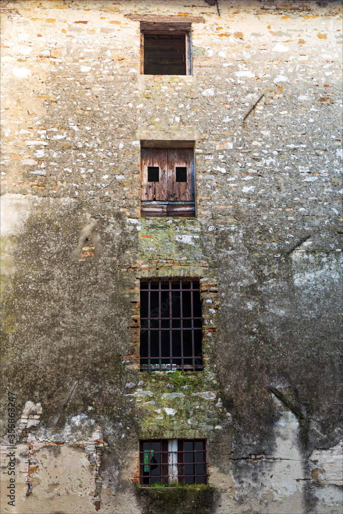 Caratteristiche finestre di antico palazzo abbandonato in città, borgo medievale di Strassoldo. 