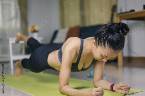 International Day of Yoga concept Asian woman doing meditation for yoga athlete plank on an exercise mat at home