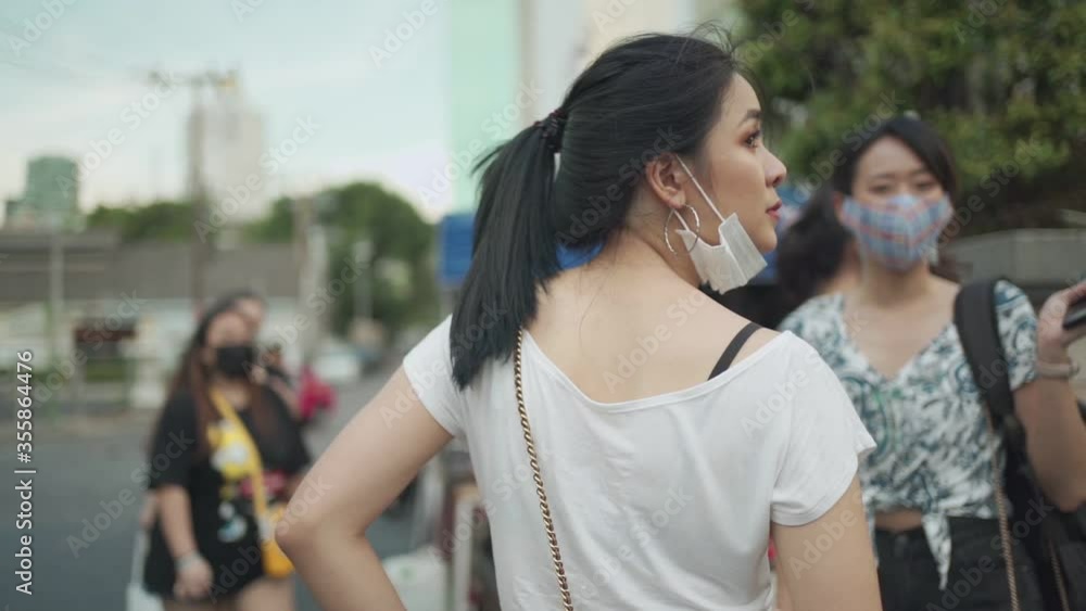 Asian women standing at street side, outdoor, pedestrian crossing background, covid-19, new normal life, two girlfriends stand outside, slow motion, urban life during world pandemic, south east asia Asian women standing at street side, outdoor, pedestrian crossing background, covid-19, new normal life, two girlfriends stand outside, slow motion, urban life during world pandemic, south east asia