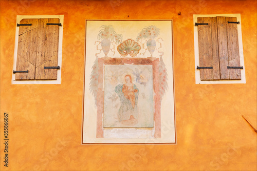 Affresco, dipinto su muro colorato. Costruzione di origine medievale nella città di Strassoldo, Udine, Friuli, Italia. Finestre con balconi chiusi. photo