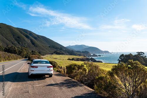 A white car on Highway 1 in California. Beautiful Californian coastline of the Pacific Ocean at Big Sur during a road trip