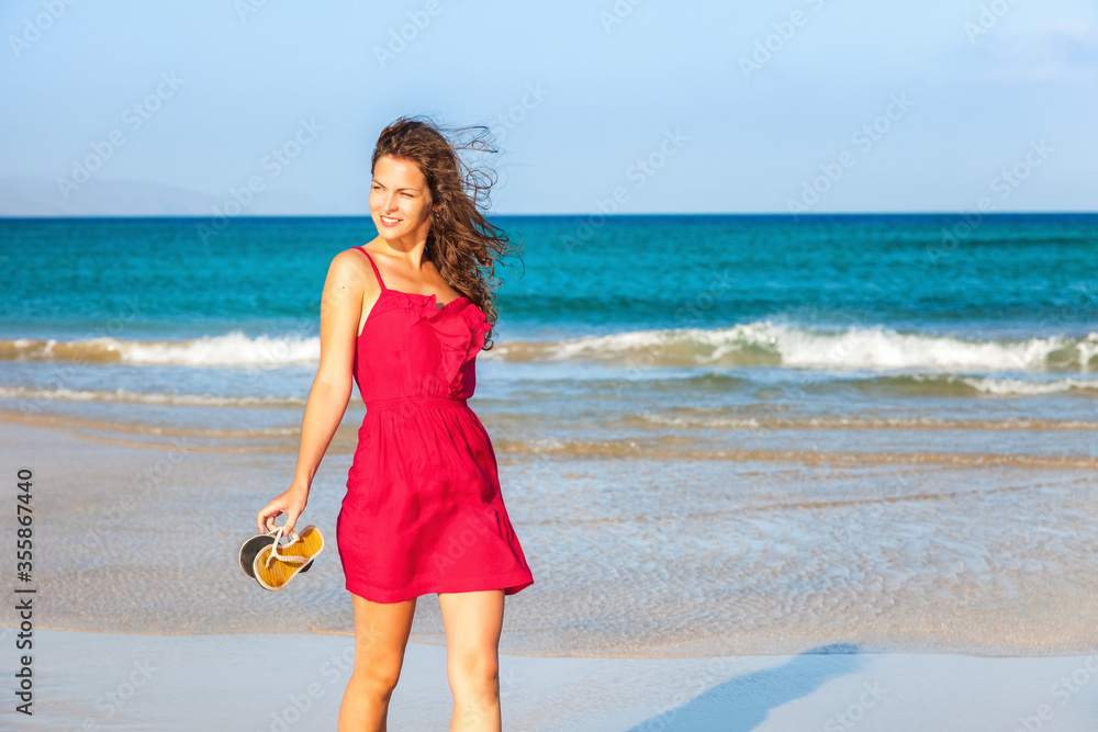 Attractive young woman in red dress enjoying the ocean beach Attractive young woman in red dress enjoying the ocean beach