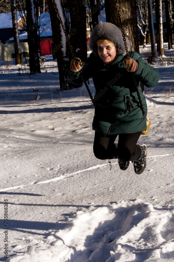 A woman swinging on a swing in winter. A woman swinging on a swing in winter.