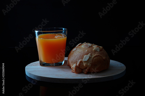 Almond bun and orange juice on black background