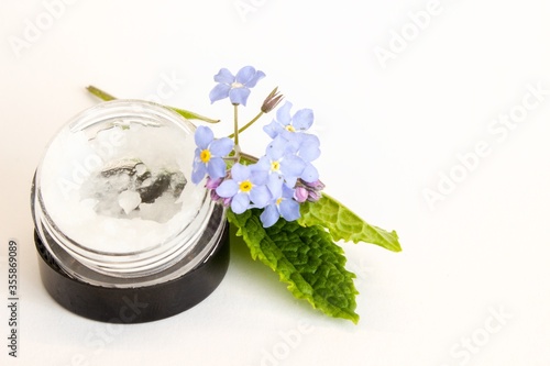 Beautiful photo of small bottle, gallipot with aloe vera gel, peppermint and flowers