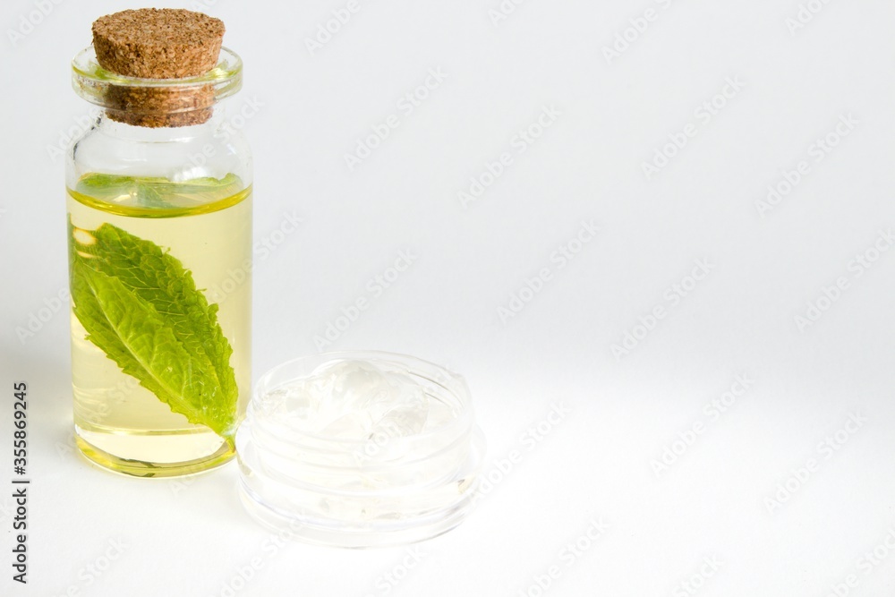 Beautiful photo of small bottle with cork stopper filled with fantastic fragrant oil, essential oils and peppermint and gallipot with aloe vera gel Beautiful photo of small bottle with cork stopper filled with fantastic fragrant oil, essential oils and peppermint and gallipot with aloe vera gel