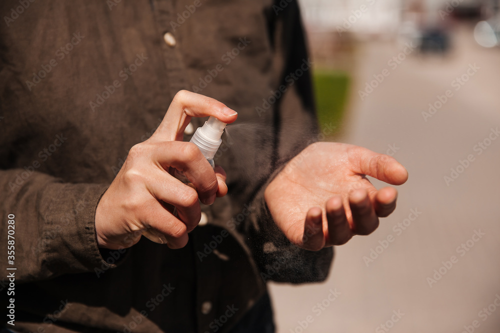 Fototapeta premium Man sprays a disinfectant on his hands