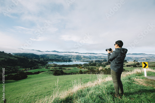 Asian tourist man photographer with camera taking pictures in mountains on foggy weather day.