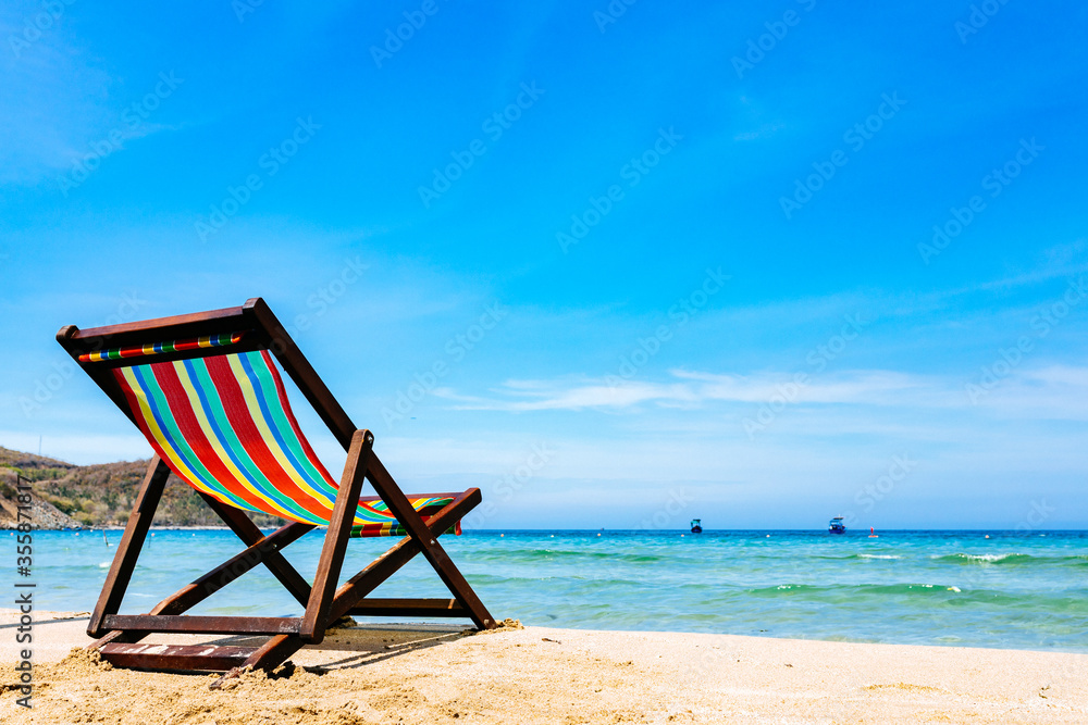 One deck chair on a sandy tropical beach with clear sea, bruise color of water and blue sky on the background One deck chair on a sandy tropical beach with clear sea, bruise color of water and blue sky on the background