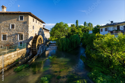 Antico mulino a pale sul fiume nel borgo medievale di Strassoldo. Italia.