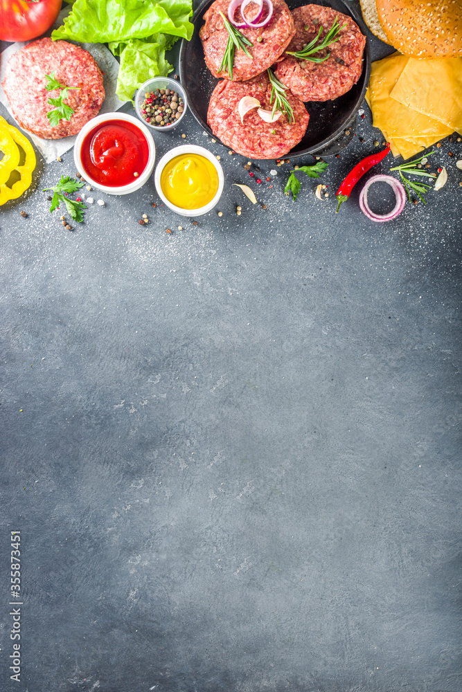 Cooking burger background. Set various cheeseburger  and beefburger ingredients - bun, tomatoes, onion, lettuce, sauces, cheese and raw burger cutlets, ready for barbecue grill. Burger bbq party fest 
