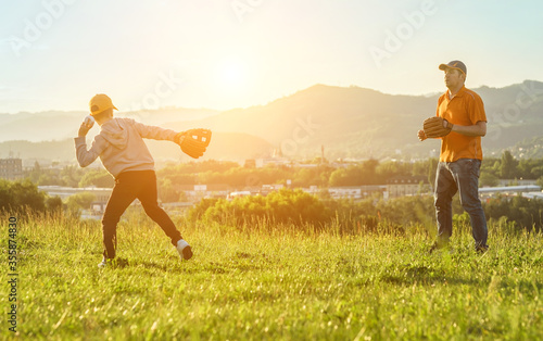 Father and son playing in baseball. Playful Man teaching Boy baseballs exercise outdoors in sunny day at public park. Family sports weekend. Father's day.