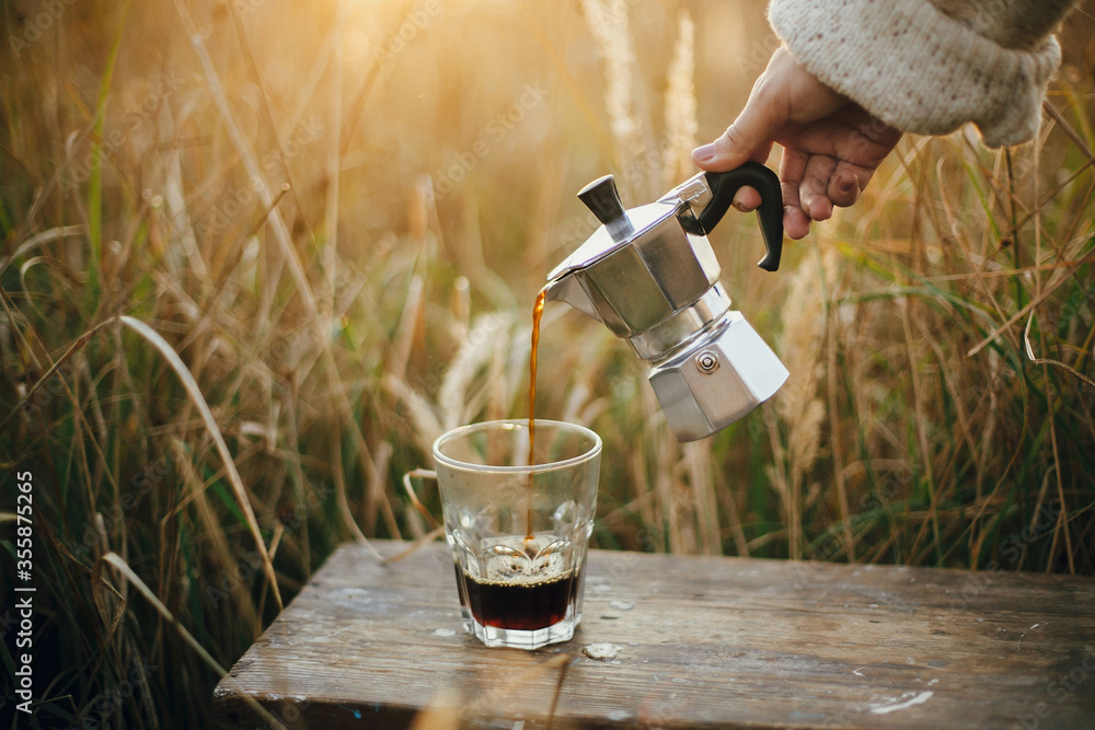 custom made wallpaper toronto digitalTraveler pouring fresh hot coffee from geyser coffee maker into glass cup in sunny warm light in rural countryside herbs. Atmospheric tranquil moment. Alternative coffee brewing in travel