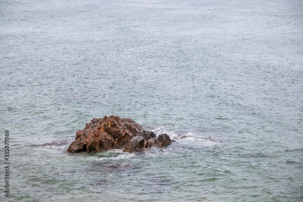 Obraz premium Rock standing in the middle of the ocean