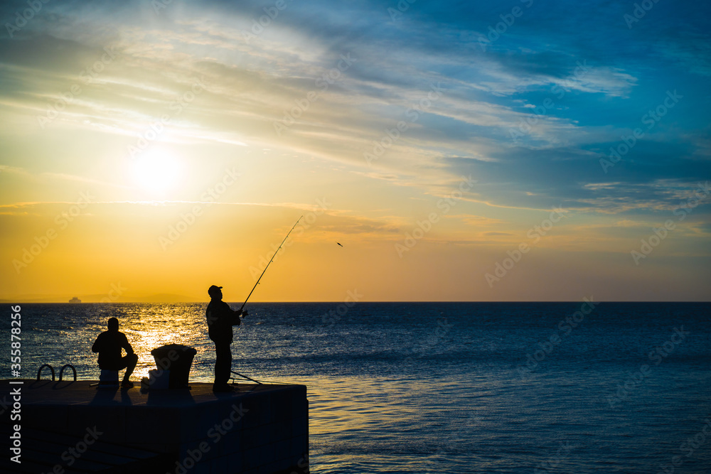 Silhouette of people fishing by the sea with twilight blue hours sky
