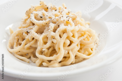 Tonnarelli cacio e pepe is a typical roman cuisine in Lazio region Italy. spaghetti with pecorino cheese and pepper on white background