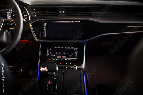 Interior of an ultra modern new luxury car. Leather chairs and wood trim, touch panels with vibration feedback and climate control. Multifunction, automatic transmission