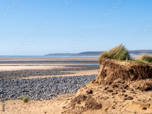 View of Northam Burrows on the Torridge and Taw estuary. Visible sand dunes and pebbles on sandy beach. Tide out. Dramatic landscape. photo